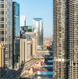 Chicago riverfront skyline with cylindrical Marina City towers, glass skyscrapers and red bridges spanning the Chicago River on a sunny day
