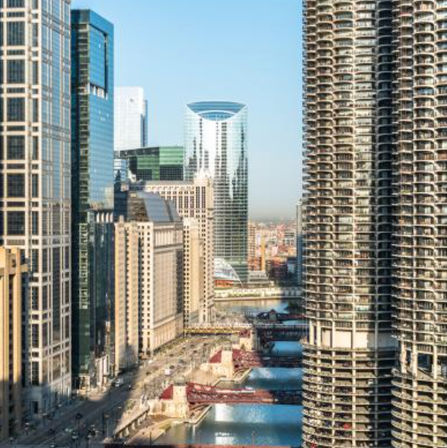 Chicago riverfront skyline with cylindrical Marina City towers, glass skyscrapers and red bridges spanning the Chicago River on a sunny day