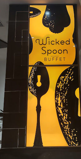 Backlit yellow-and-black indoor restaurant sign featuring oversized stylized spoon silhouettes and the word buffet in playful lettering, modern dining decor