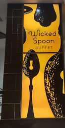 Backlit yellow-and-black indoor restaurant sign featuring oversized stylized spoon silhouettes and the word buffet in playful lettering, modern dining decor