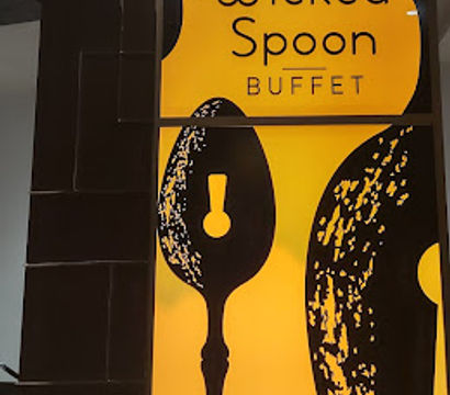 Backlit yellow-and-black indoor restaurant sign featuring oversized stylized spoon silhouettes and the word buffet in playful lettering, modern dining decor