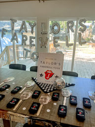 Silver balloon letters spell TAYLOR'S FAREWELL TOUR above a wooden table in Austin, TX, with a welcome sign, mirrored disco ball, checkered cloth, face-cutout paddle favors and black tour koozies for a backyard farewell party.