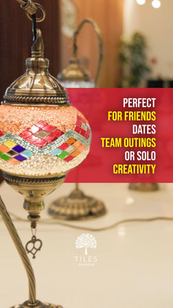 Ornate mosaic glass pendant lamp with brass fittings on a workshop table, blurred lamps in the background and a red banner reading “Perfect for friends, dates, team outings or solo creativity”.