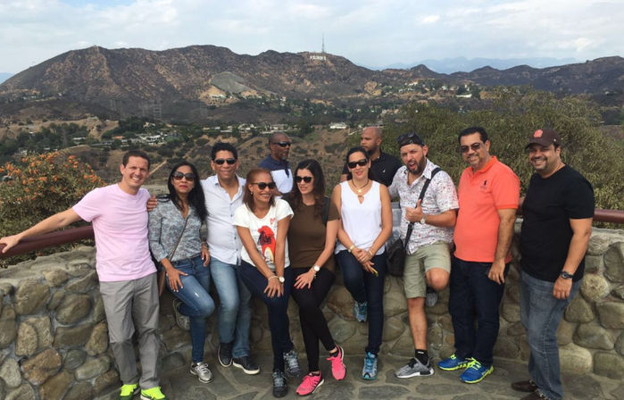 Group of adults smiling and posing at a Hollywood Hills overlook in Los Angeles with the Hollywood Sign visible on the hillside
