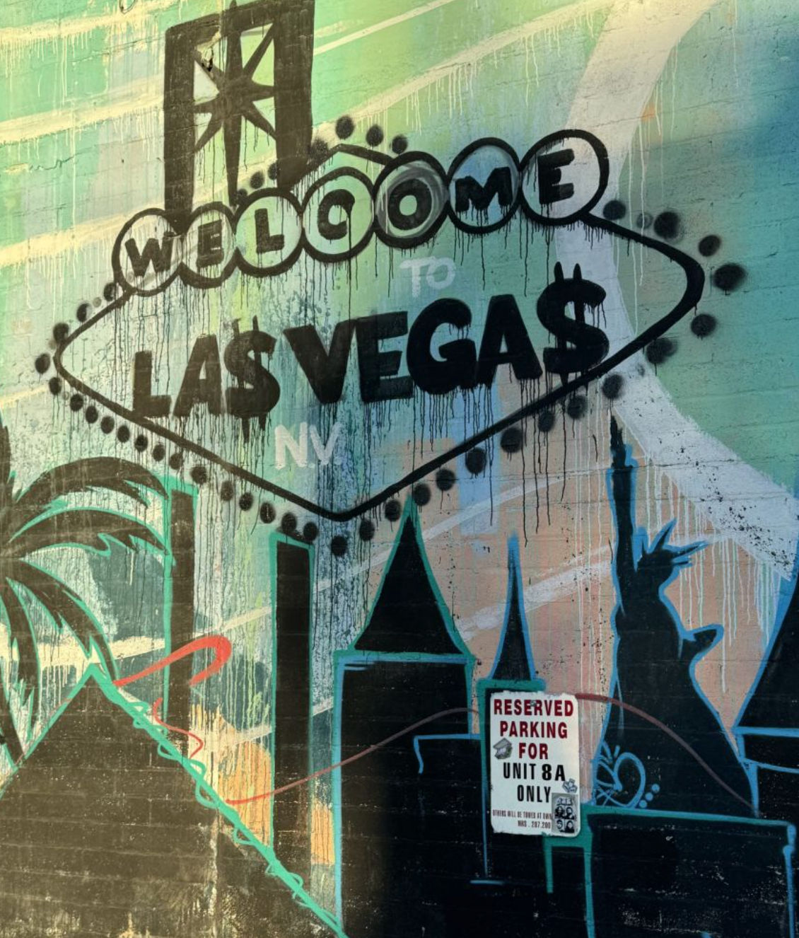 Playful Las Vegas street-art mural of a dripping "Welcome to Las Vega$" sign painted on a textured wall, featuring palm trees, stylized skyline and a Statue of Liberty silhouette — vibrant urban graffiti in Nevada.