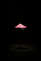 Minimalist cocktail: matte black coupe glass on a dark background topped with a vibrant pink foam mound