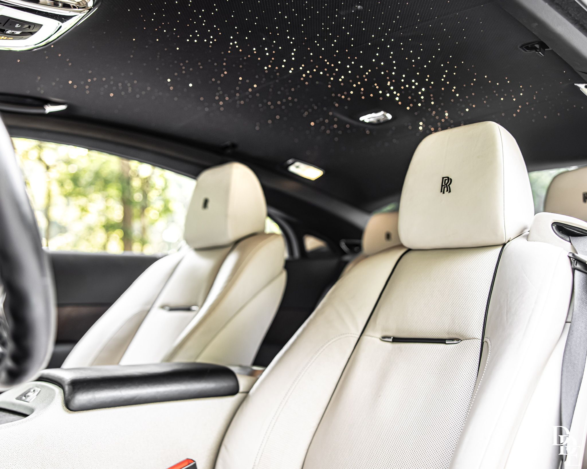 Luxury car interior with white leather front seats and a dazzling starlight LED headliner, close-up of plush cabin details