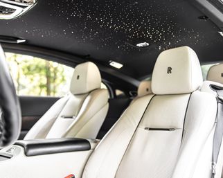 Luxury car interior with white leather front seats and a dazzling starlight LED headliner, close-up of plush cabin details