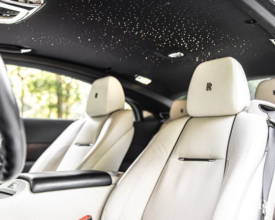 Luxury car interior with white leather front seats and a dazzling starlight LED headliner, close-up of plush cabin details