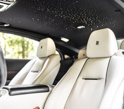 Luxury car interior with white leather front seats and a dazzling starlight LED headliner, close-up of plush cabin details