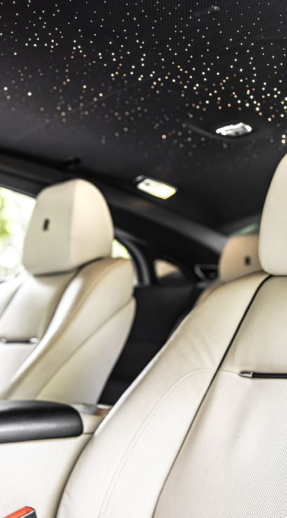 Luxury car interior with white leather front seats and a dazzling starlight LED headliner, close-up of plush cabin details