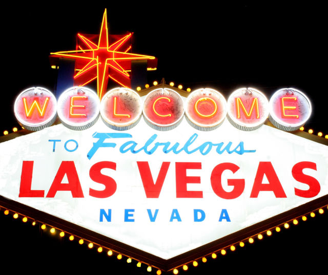 Glowing vintage neon sign reading "Welcome to Fabulous Las Vegas Nevada" with a red starburst topper lit up against a black night sky