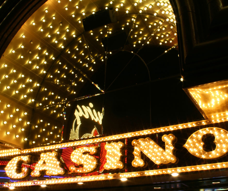 Glowing golden vintage-bulb casino marquee beneath an arched mirrored ceiling, bright nightlife signage and reflections at night