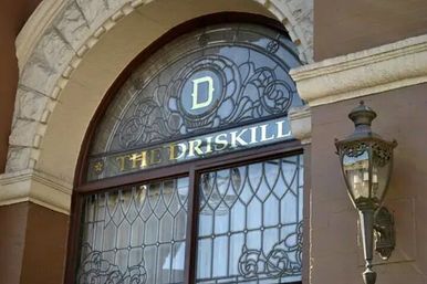 Charming historic arched entrance with decorative stained-glass panels, a gold-lettered name band and an ornate antique wall lantern.