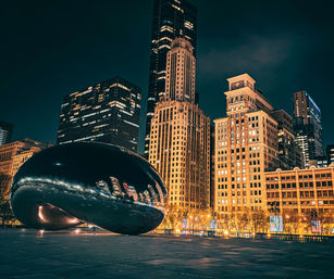 Night view of Chicago skyline and illuminated skyscrapers reflected in the mirror-like Cloud Gate sculpture ('The Bean') in Millennium Park
