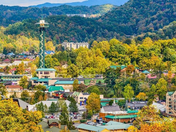 Aerial view of a mountain town in autumn with an observation tower, green-roofed buildings and vibrant fall foliage