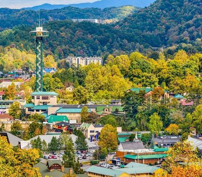 Aerial view of a mountain town in autumn with an observation tower, green-roofed buildings and vibrant fall foliage