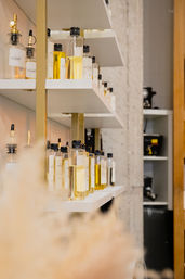 Chic salon shelves lined with clear glass bottles of golden cosmetic oils and sprayers on white shelves with gold accents