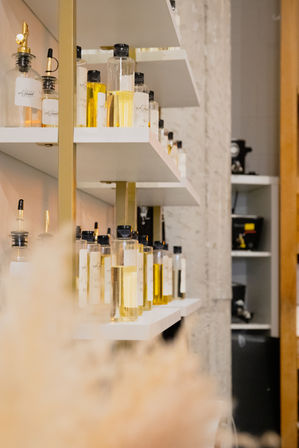 Chic salon shelves lined with clear glass bottles of golden cosmetic oils and sprayers on white shelves with gold accents