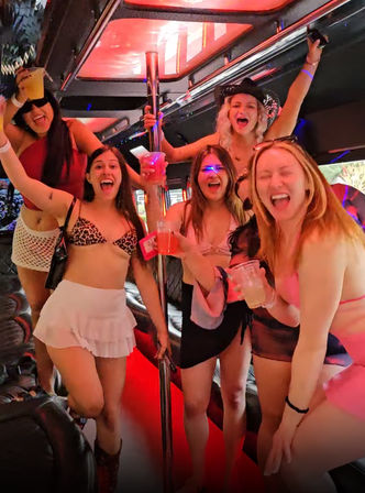 Neon-lit party bus interior with a group of women in swimsuits and party outfits cheering with drinks around a dance pole, celebrating a girls' night out.