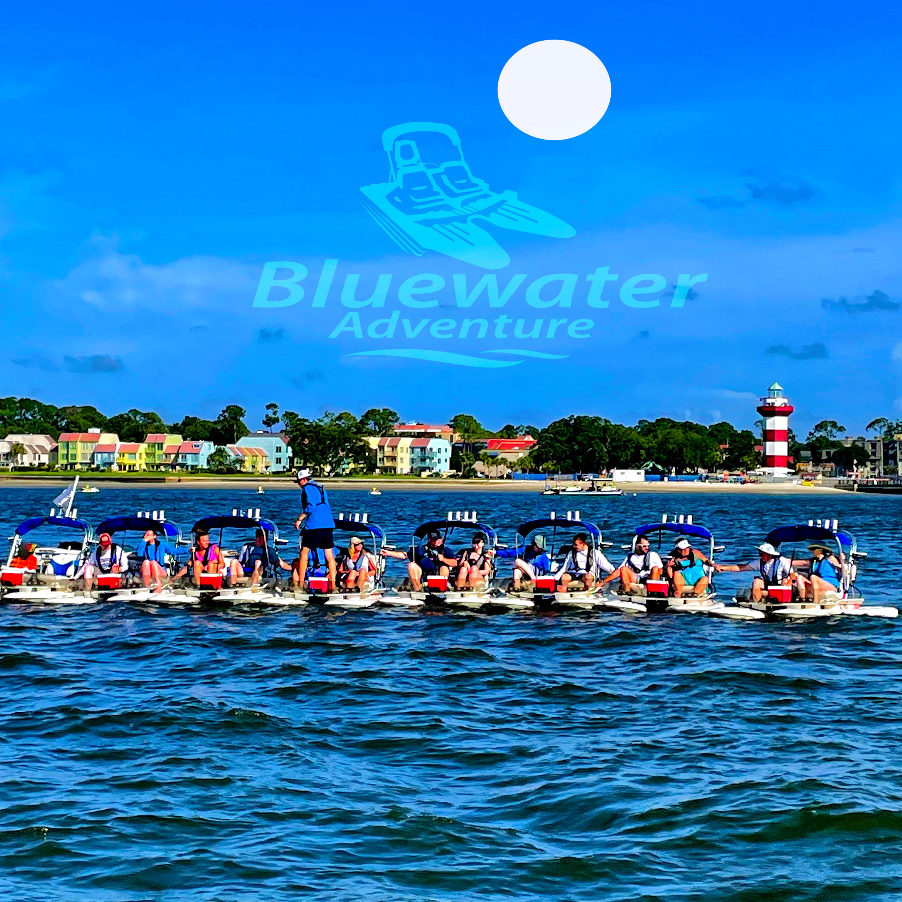 Line of pedal boats with people in life jackets on blue coastal waters, colorful beachfront houses and a red-and-white lighthouse under a bright sky.