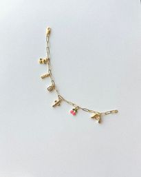 Gold link charm bracelet flat-lay on white background featuring a cactus charm, 'MAMA' bar, small crystal, bead cluster, pink enamel cherries and a gold high-heel charm