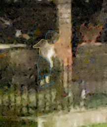 Grainy nighttime backyard scene with a small humanoid figure outlined in blue and yellow wearing a hat and boots next to a wooden post and fence, and a red-outlined dog-like face sketched on the right