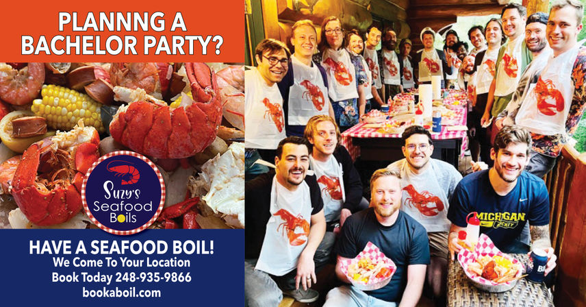 Group of smiling men at a bachelor party on a wooden porch enjoying a catered seafood boil—lobster, crab, corn and sausage on checkered tables, many wearing bibs.