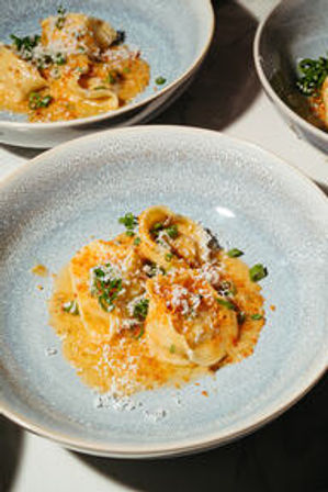 Restaurant-style ricotta ravioli in a creamy tomato-orange sauce topped with grated Parmesan and chopped chives, served in a textured light-blue ceramic bowl
