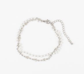 Delicate silver double-strand bracelet with tiny star charms, small white pearl beads, lobster clasp and extender chain on a white background