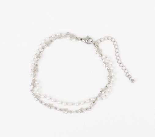 Delicate silver double-strand bracelet with tiny star charms, small white pearl beads, lobster clasp and extender chain on a white background