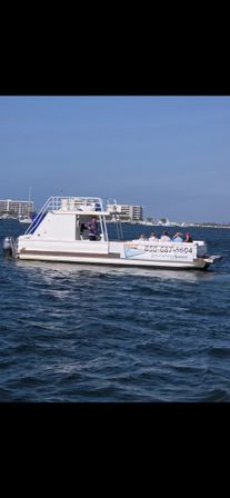 White party pontoon cruising blue waters off Destin, Florida, passengers relaxing near beachfront condominiums on a sunny day
