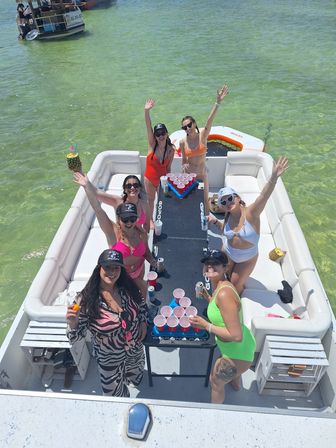 Aerial view of a lively pontoon boat party on clear green water, people in swimsuits playing beer pong with red cups and pineapple drinks