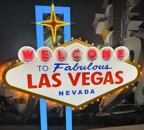 Bright retro 'Welcome to Fabulous Las Vegas, Nevada' neon sign with glowing starburst, round bulbs and bold red and blue lettering against a dark backdrop.