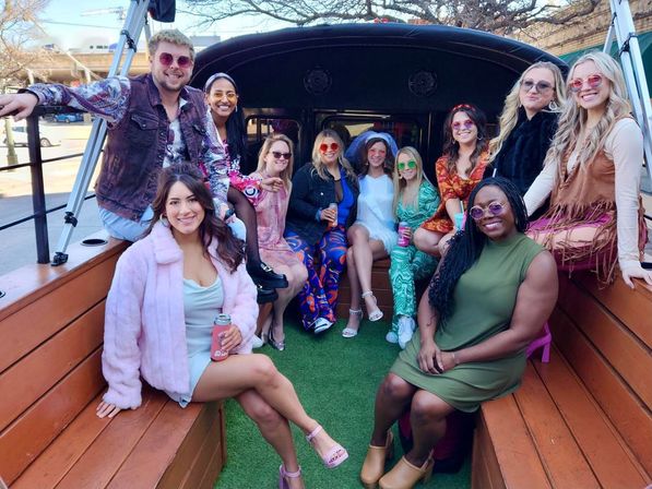 Group of friends on a wooden city party trolley, wearing colorful retro outfits and sunglasses, smiling and holding drinks for a festive outing