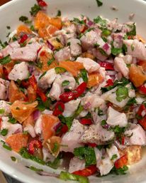 Zesty citrus fish ceviche with diced white fish, mandarin orange segments, red chili, red onion and cilantro in a white bowl