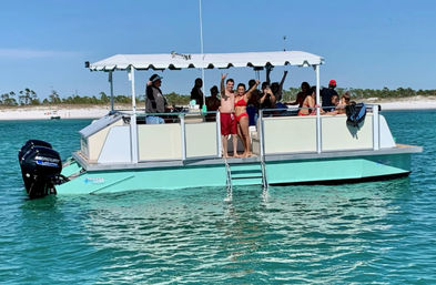 Smiling group in swimsuits on a teal pontoon boat with canopy, waving and lounging in clear turquoise water off a white sandy beach on a sunny day.
