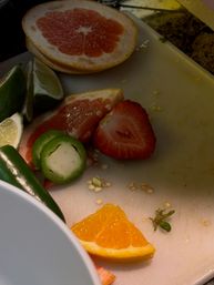 Sliced grapefruit, lime wedges, orange slice, strawberry and jalapeño rings on a white cutting board — colorful citrus and pepper prep in a home kitchen