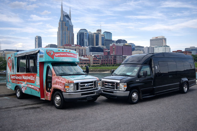 Bright turquoise open-sided tour shuttle and black passenger van parked by the river with downtown Nashville skyline and the twin-spired AT&T “Batman” building under a blue sky, ready for city tours.