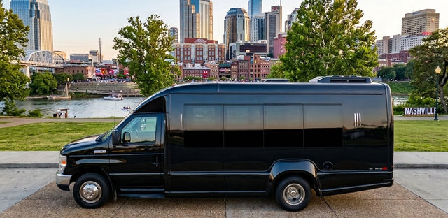 Black passenger shuttle parked on the Nashville riverfront with the river and downtown skyline at sunset.