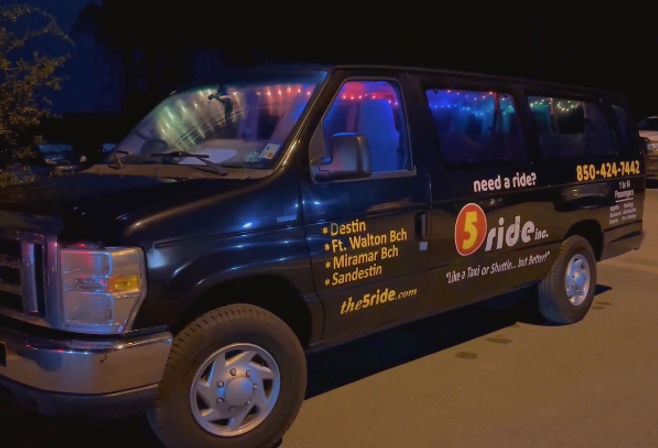 Black shuttle van parked at night with colorful interior string lights, listing Destin and nearby Florida beach towns