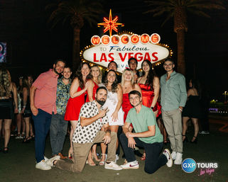 Cheerful group posing at night in front of the neon "Welcome to Fabulous Las Vegas" sign, festive evening on the Las Vegas Strip
