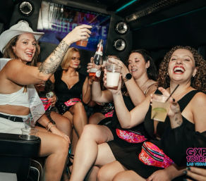 Group of women laughing and toasting drinks inside a party limo during a bachelorette celebration