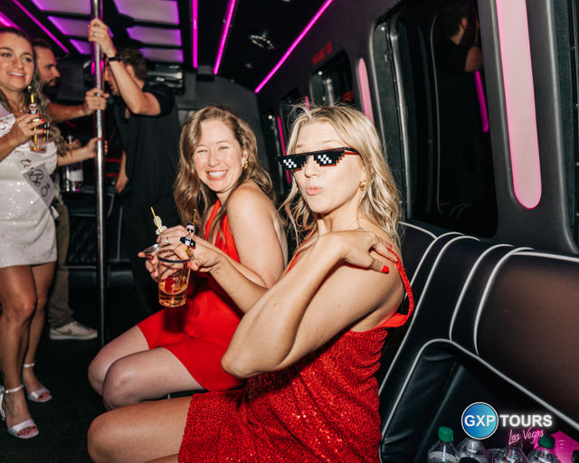 Friends in red dresses enjoying drinks on a pink neon-lit party bus in Las Vegas, playful vibe with pixelated sunglasses and laughter