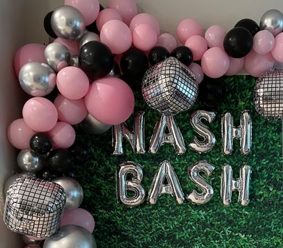 Festive pink, black, and silver balloon garland framing a faux boxwood party backdrop with mirrored disco-cube balloons and silver letter balloons spelling NASH BASH.