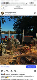 Lakeside Nashville picnic at sunset — wooden table styled with taper candles, vases of roses and baby’s breath, charcuterie board, vintage record player and woven placemats