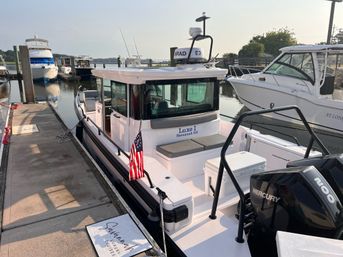 Compact white cabin powerboat with outboard engine and American flag tied to a marina dock in Savannah, GA in soft morning light.