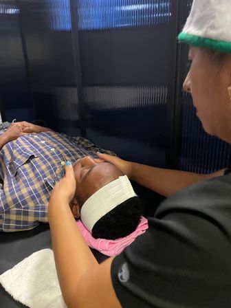 Relaxing facial massage in a spa treatment room — therapist gently massaging a client’s forehead while the client lies on a towel‑wrapped headrest