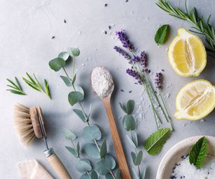 Natural spa flat lay with lemon halves, lavender sprigs, eucalyptus stems, mint leaves, sea salt in a wooden spoon and bowl, and an eco‑friendly wooden brush on a light background — DIY skincare and wellness aesthetic.