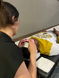 Technician applying pink cooling eye patches to a client lying on a spa treatment table during a skincare facial.
